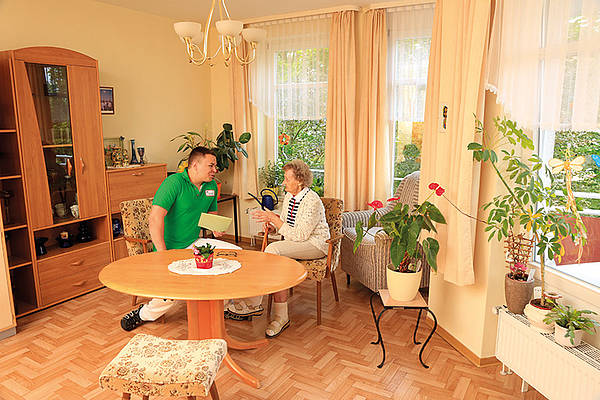 Seniorin mit Pfleger am Tisch